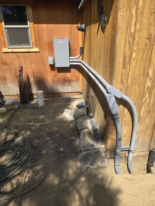 Conduit run from underground into an outbuilding disconnect on a rural property